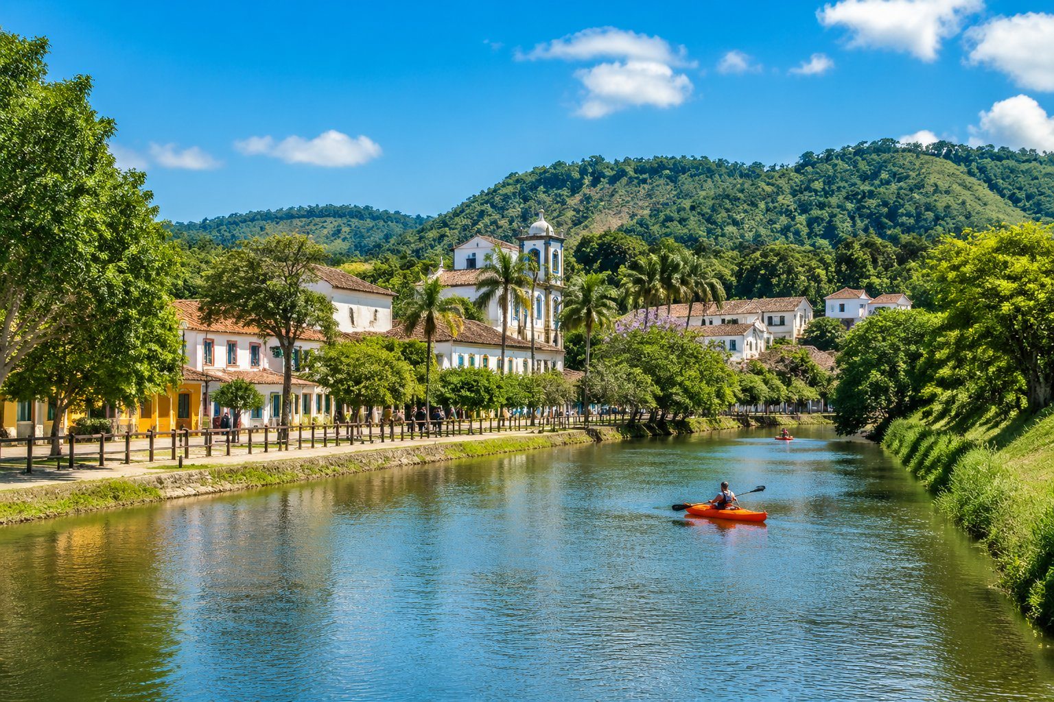 Vista de Guararema com casas coloridas, colinas verdes, rio tranquilo e pessoas aproveitando atividades ao ar livre.
